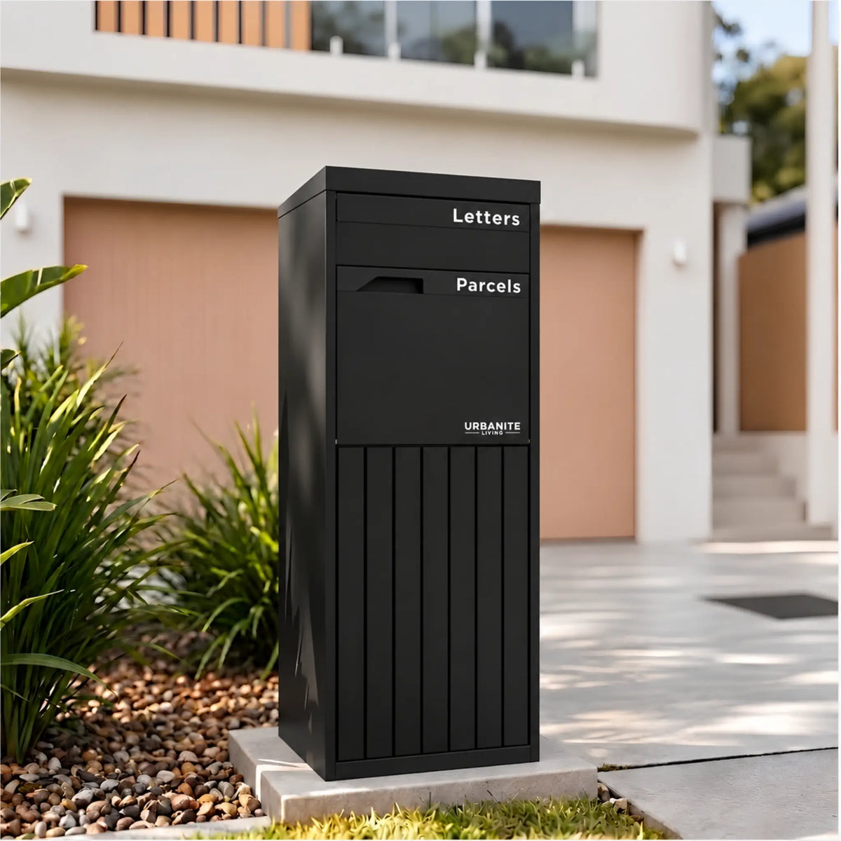 Urbanite Living Corella Extra Tall freestanding parcel letterbox in black beside a driveway at a home.