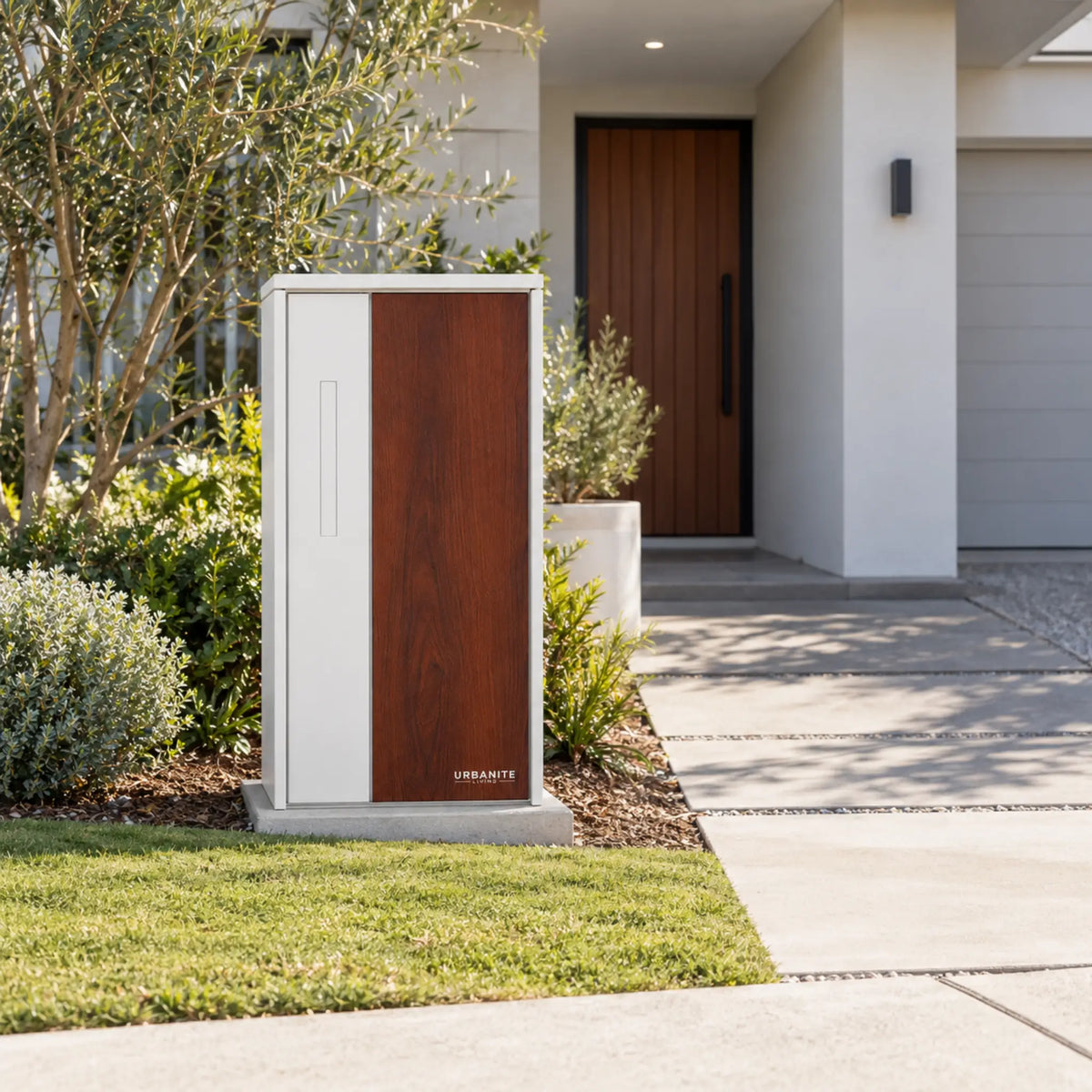 Urbanite Living The Don Extra Wide Parcel Letterbox in white with dark wood look metal front panel beside a landscaped front path. 