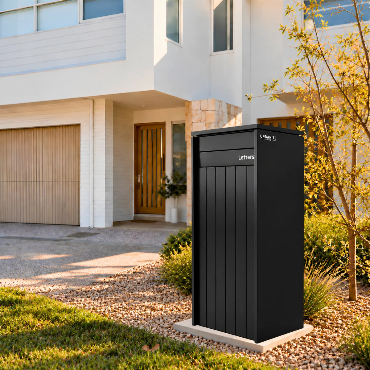 Heron Extra Wide parcel letterbox in a black finish in the front garden of a two-storey home Urbanite Living.