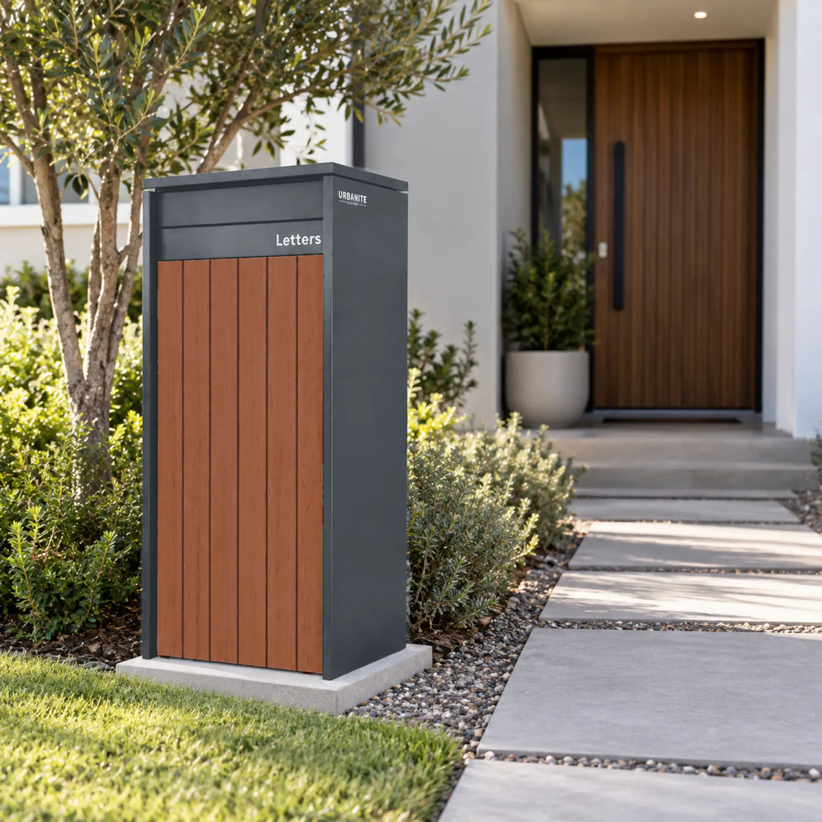 Urbanite Living Heron Extra Wide freestanding parcel letterbox in charcoal with dark wood front panels beside a garden path.