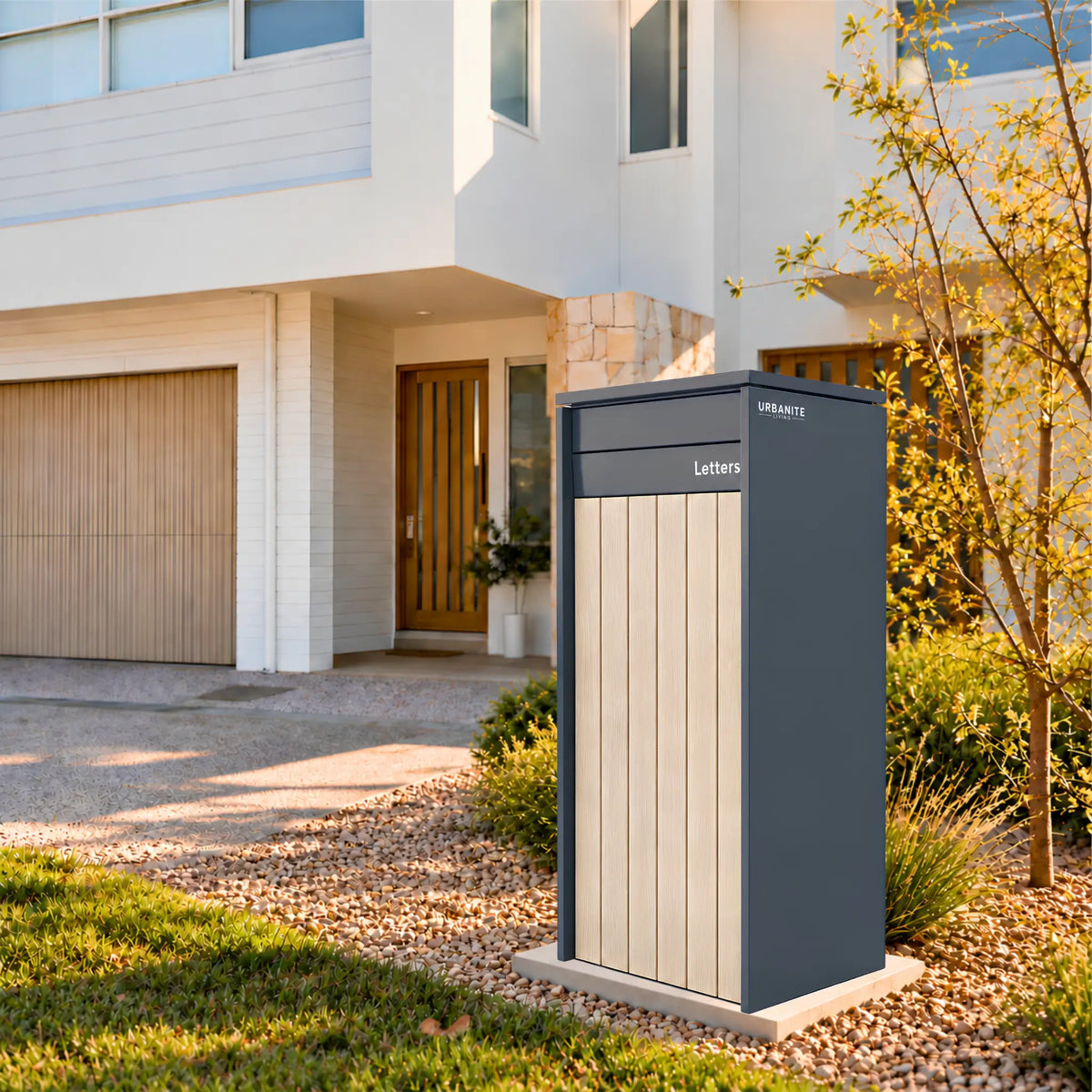 Heron Extra Wide parcel letterbox in charcoal with light wood front panels in the front garden of a two-storey home - Urbanite Living.