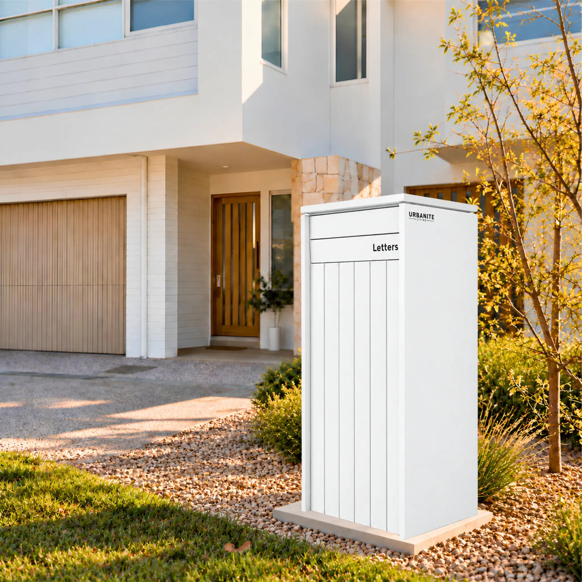 Heron Extra Wide parcel letterbox by Urbanite Living in a white finish in the front garden of a two-storey home.