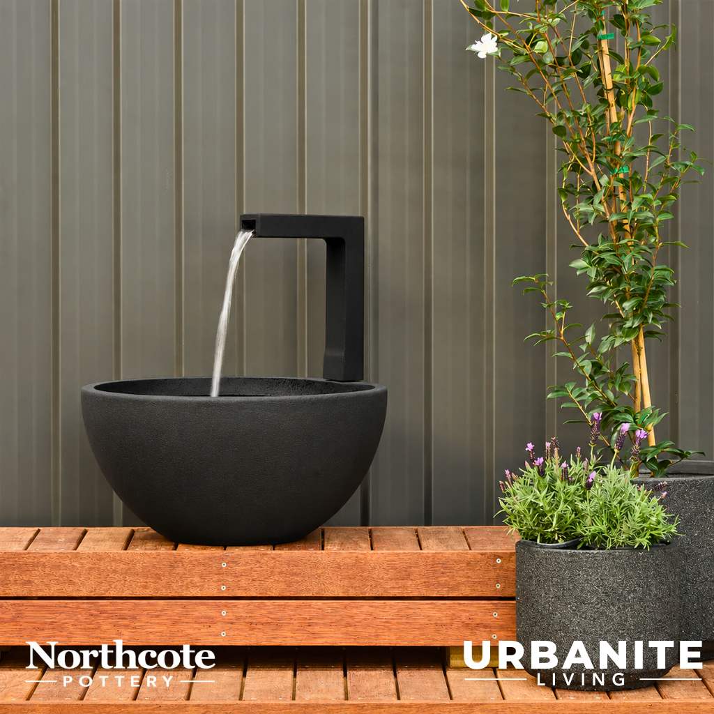 Black patio pond with flowing water sitting on a timber deck.