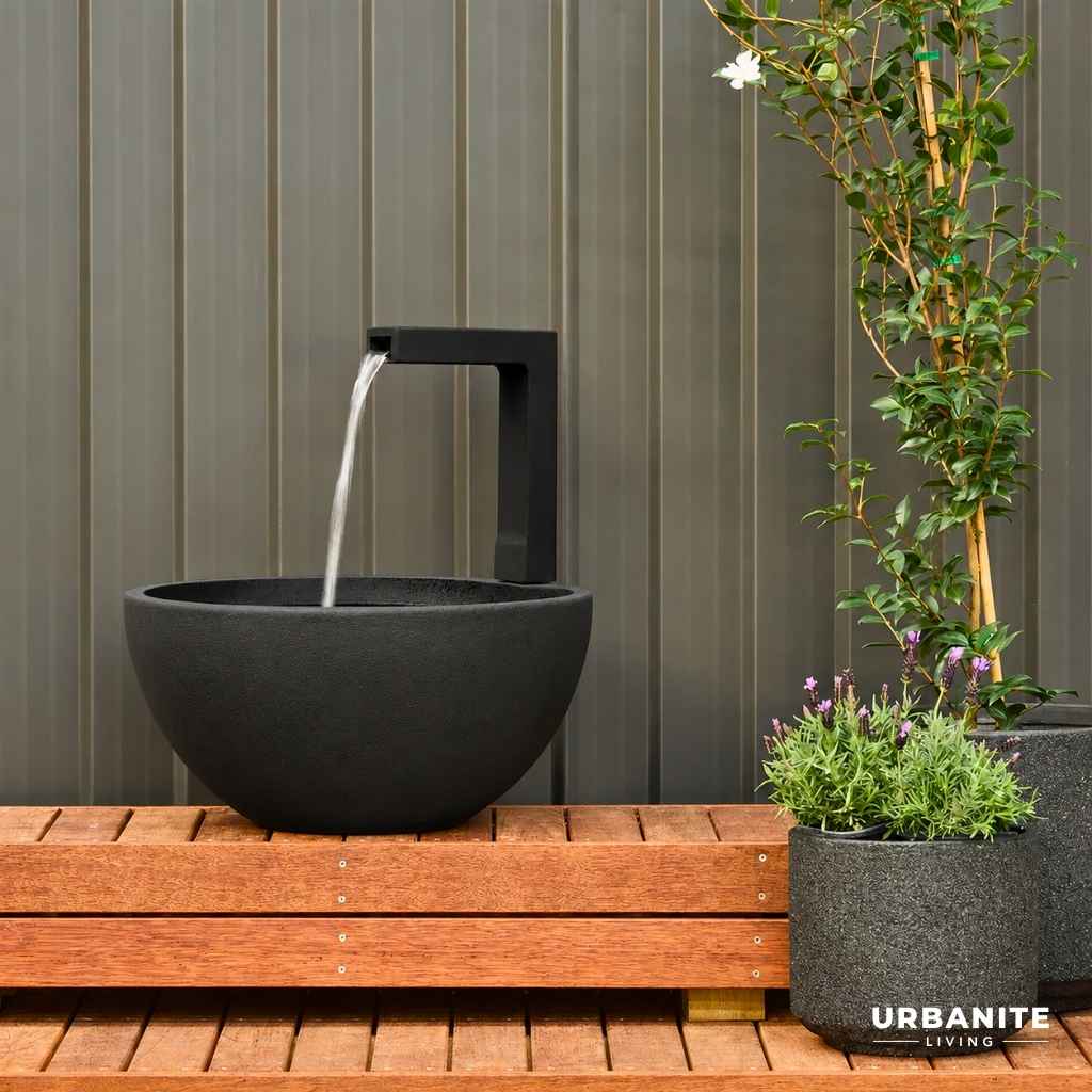 Medium Black patio spout pond with flowing water sitting on a timber deck.