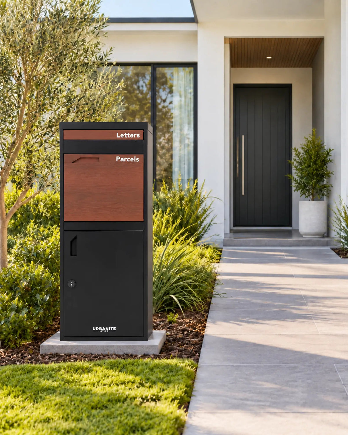 Urbanite Living Osprey Extra Tall freestanding parcel letterbox in black with dark timber look front panels beside a front path at a home.
