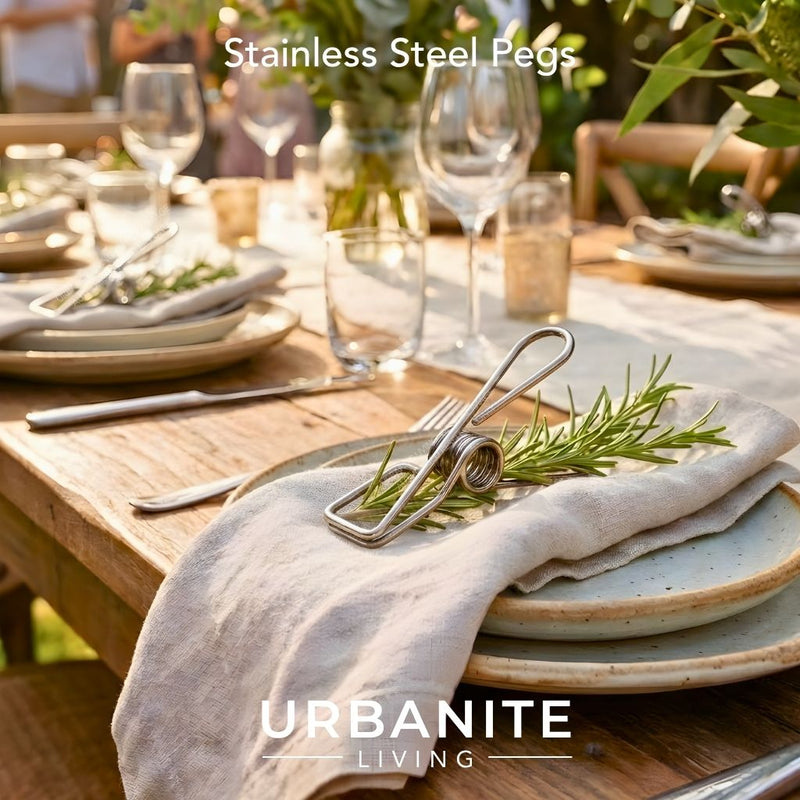 Stainless Steel Marine Grade 316 Peg, timber table dinner setting holding down a sprig of rosemary, with linen napkins, earthy tone plates wine and water glasses with the glow of a setting sun. By Urbanite Living.