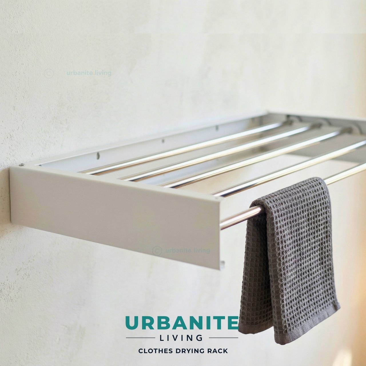 Urbanite Living white wall mounted clothes drying rack installed on wall with grey towel hanging.