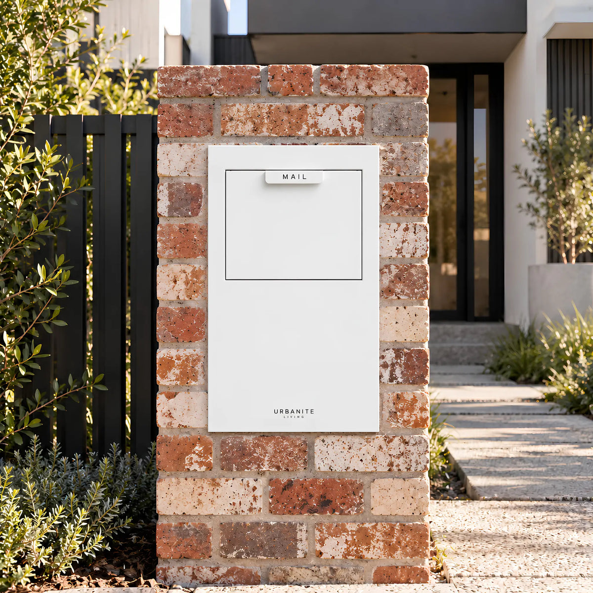 Urbanite Living Wren parcel letterbox in white, built into a red brick pillar at a home's front entrance.